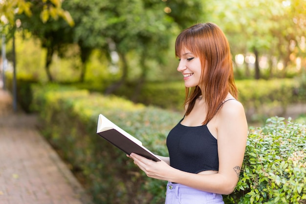 Young pretty redhead woman at outdoors holding a notebook