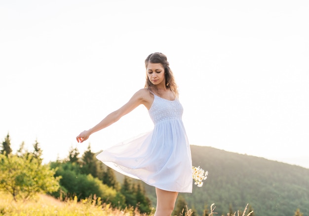 Young pretty romantic girl with bouquet of wildflowers on the background of blue sky