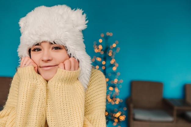 Young pretty smiling woman celebrating dressed warm sweater and woolen hat, standing posing