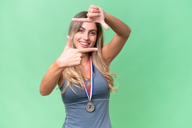 Young pretty sport Uruguayan woman with medals over isolated background focusing face Framing symbol