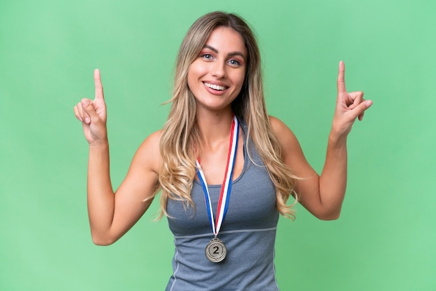 Young pretty sport Uruguayan woman with medals over isolated background pointing up a great idea