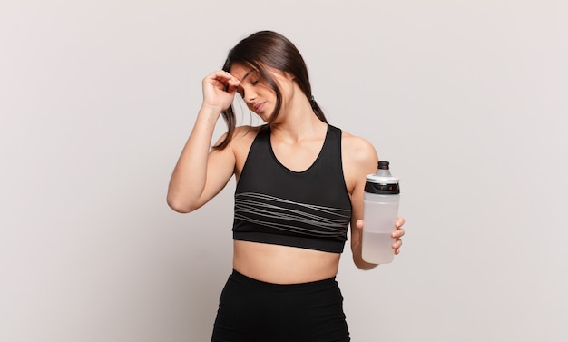 Young pretty sport woman sad expression and holding a water bottle drink