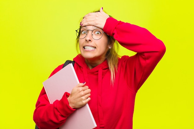 Young pretty student panicking over a forgotten deadline, feeling stressed, having to cover up a mess or mistake