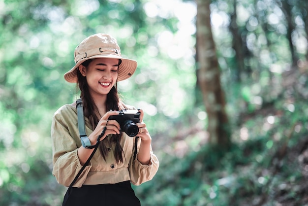 Young pretty taking photo by digital camera she looking picture and smile with happy while camping in forest Young Asian group women travel outdoor camping