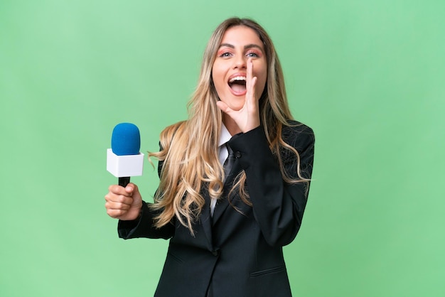 Young pretty Uruguayan tv presenter over isolated background shouting with mouth wide open