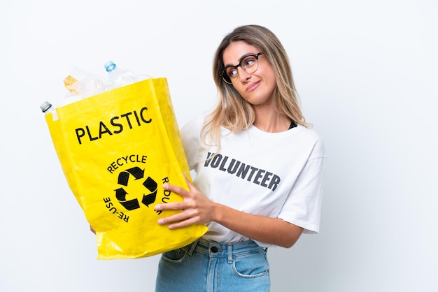 Young pretty Uruguayan woman holding a bag full of plastic bottles to recycle isolated on white background with sad expression