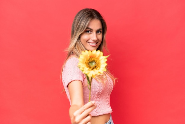 Young pretty Uruguayan woman holding sunflower isolated on background with happy expression