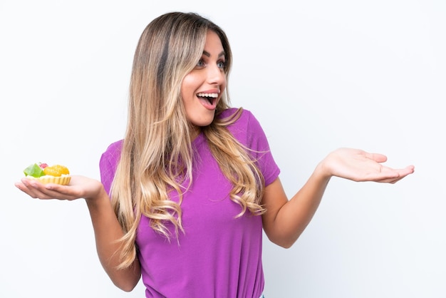 Young pretty Uruguayan woman holding a tartlet isolated on white background with surprise facial expression