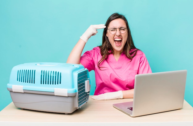 young pretty veterinarian woman with a laptop and pet cage