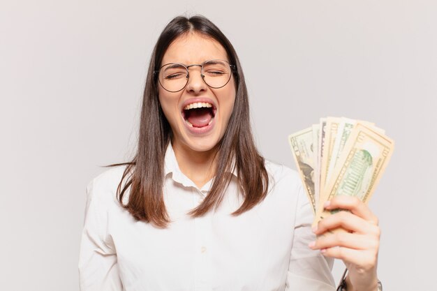 Young pretty woman angry expression and holding dollar banknotes