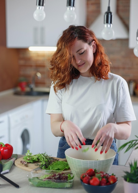 Young pretty woman blogger shoots a video of a salad recipe on a smartphone camera