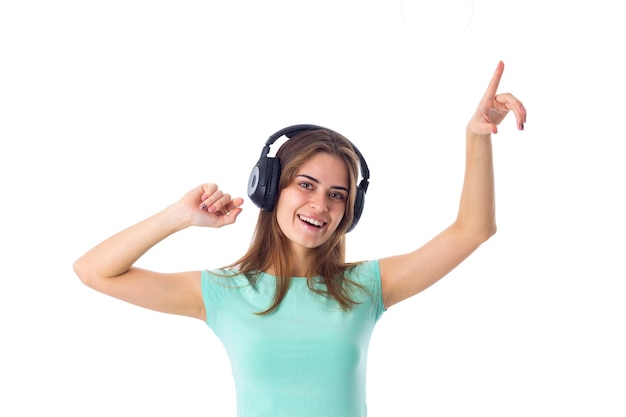 Young pretty woman in blue Tshirt listening to the music in black headphones in studio