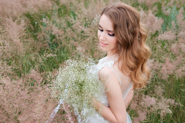 Young pretty woman (bride) in white wedding dress outdoors, hairstyle