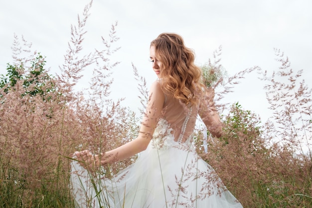 Young pretty woman (bride) in white wedding dress outdoors, hairstyle