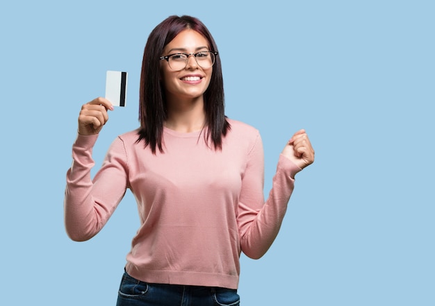 Young pretty woman cheerful and smiling, very excited holding the new bank card