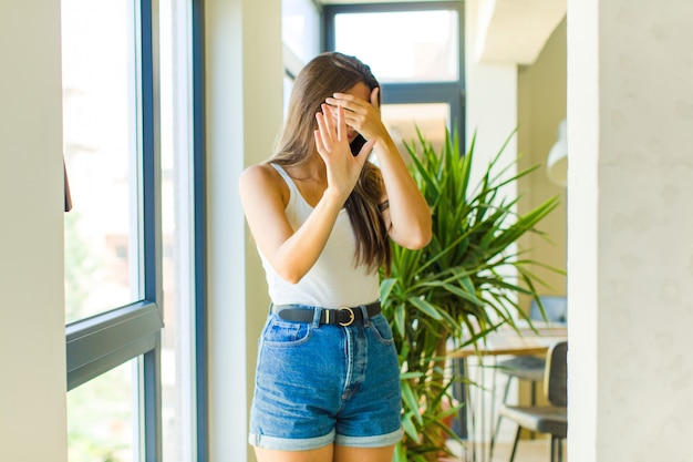 Young pretty woman covering face with hand