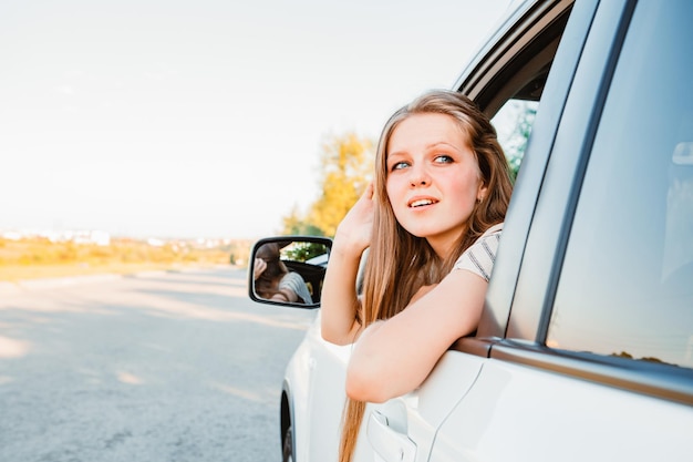 Young pretty woman driving car on sunset