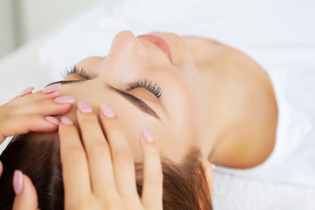 Young pretty woman enjoying face massage procedure.