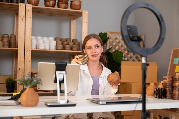 A young pretty woman entrepreneur live streaming to sale craft products to customers in her shop