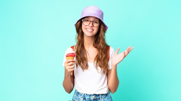 Young pretty woman feeling happy, surprised realizing a solution or idea holding an ice cream. summer concept