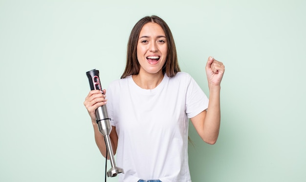 Young pretty woman feeling shocked,laughing and celebrating success. hand mixer concept