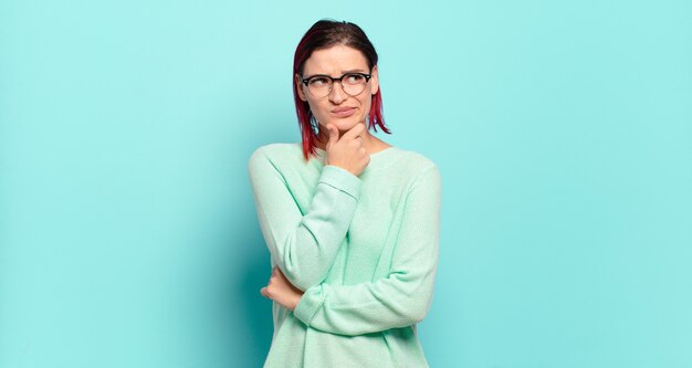 Young pretty woman gesturing on colored wall