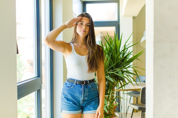 Young pretty woman greeting the camera with a military salute in an act of honor and patriotism, showing respect