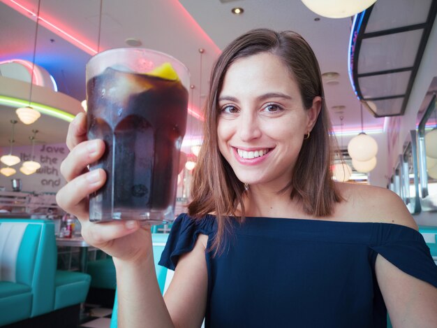 Young pretty woman having a cola drink