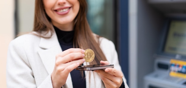 Young pretty woman holding a Bitcoin at outdoors