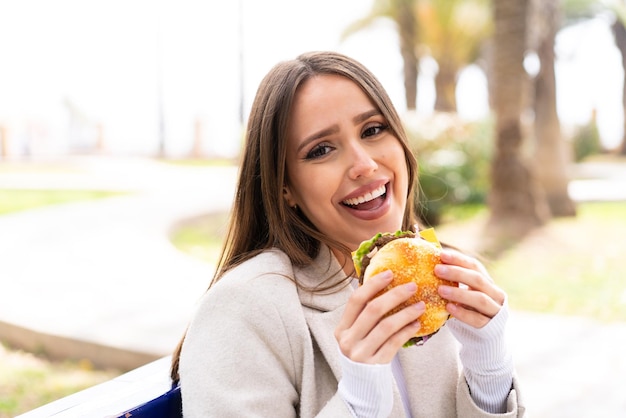 Young pretty woman holding a burger at outdoors