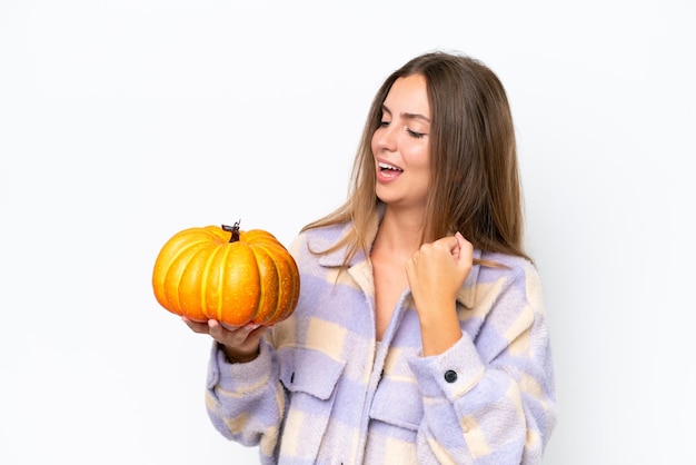 Young pretty woman holding a pumpkin isolated on white background celebrating a victory