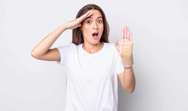 young pretty woman looking happy, astonished and surprised. hand bandage concept