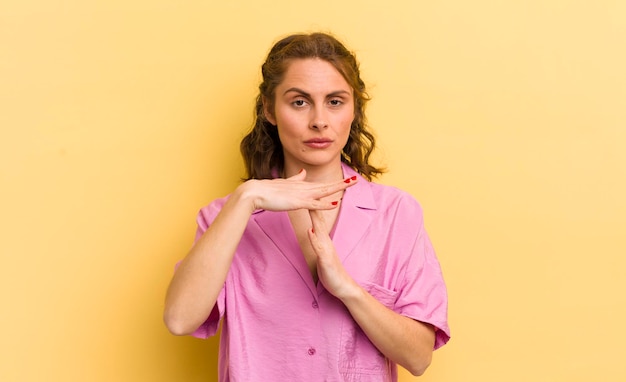 Young pretty woman looking serious stern angry and displeased making time out sign