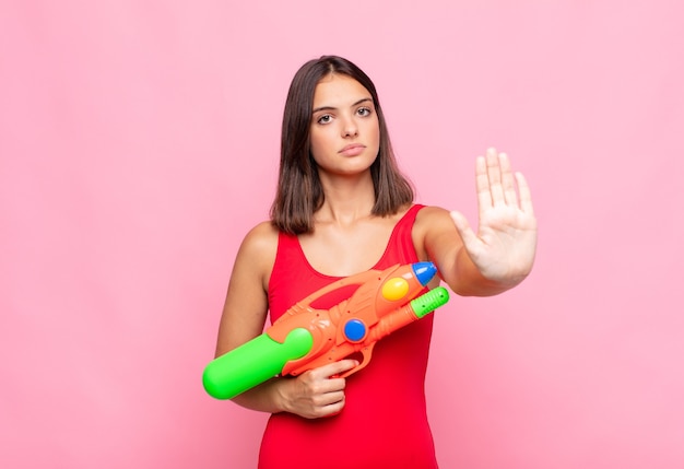 Young pretty woman looking serious, stern, displeased and angry showing open palm making stop gesture