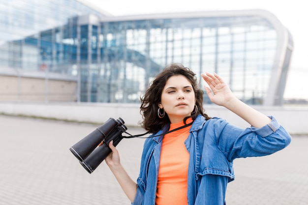 Young pretty woman looks away with a binocular in her hands