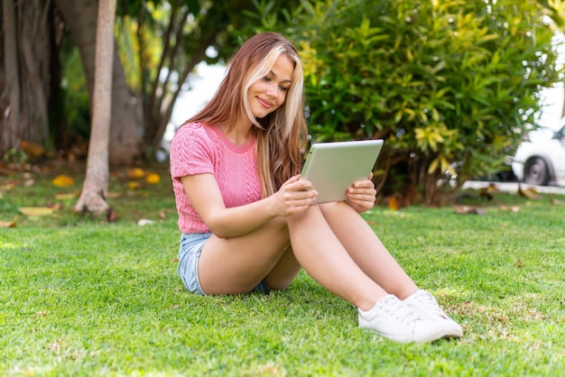 Young pretty woman at outdoors holding a tablet