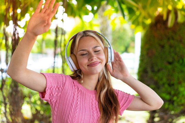 Young pretty woman at outdoors listening music and dancing