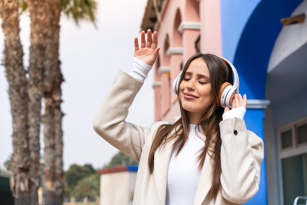 Young pretty woman at outdoors listening music and dancing