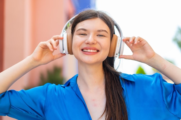 Young pretty woman at outdoors listening music