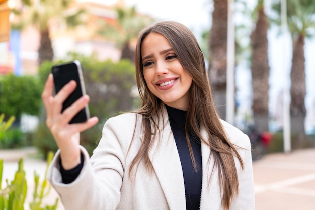 Young pretty woman at outdoors making a selfie with mobile phone