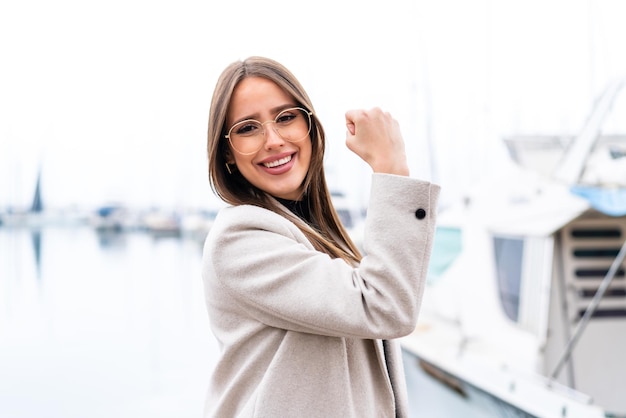 Young pretty woman at outdoors With glasses and celebrating a victory