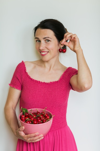 Young pretty woman in pink dress play with berries