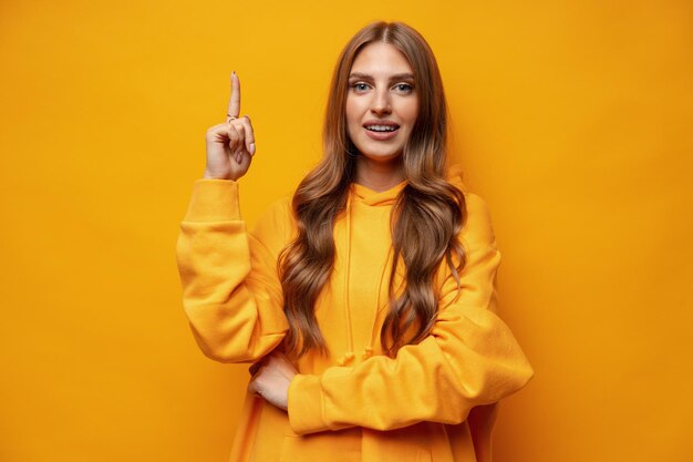 Photo young pretty woman pointing at copy space in studio