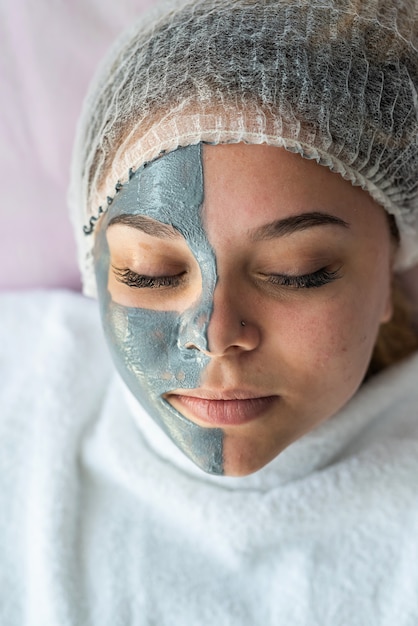 Young pretty woman receiving facial mask at beauty salon