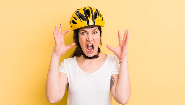 Young pretty woman screaming with hands up in the air bike helmet concept