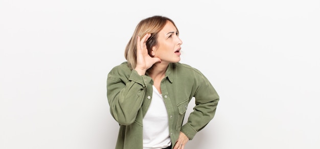 Young pretty woman smiling, looking curiously to the side, trying to listen to gossip or overhearing a secret