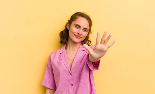 Young pretty woman smiling and looking friendly showing number five or fifth with hand forward counting down