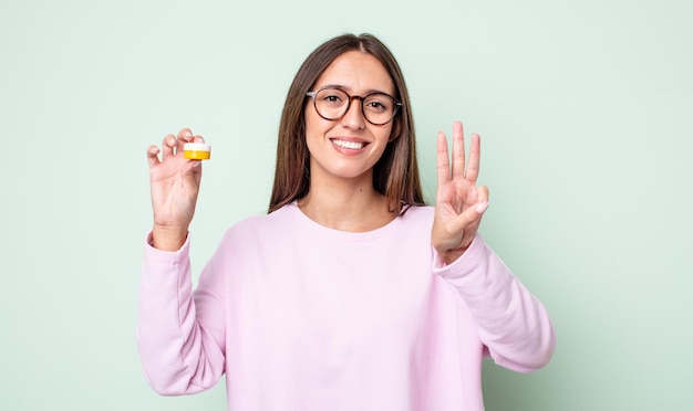 Young pretty woman smiling and looking friendly, showing number three. contact lenses concept