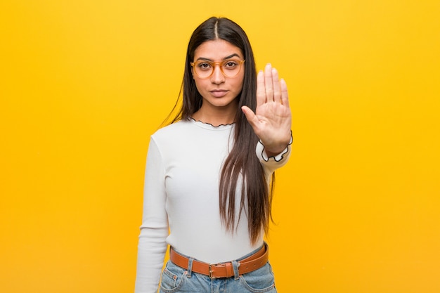 Young pretty woman standing with outstretched hand showing stop sign, preventing you