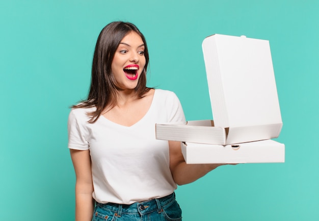 Young pretty woman surprised expression and holding take away pizzas and holding take away pizzas